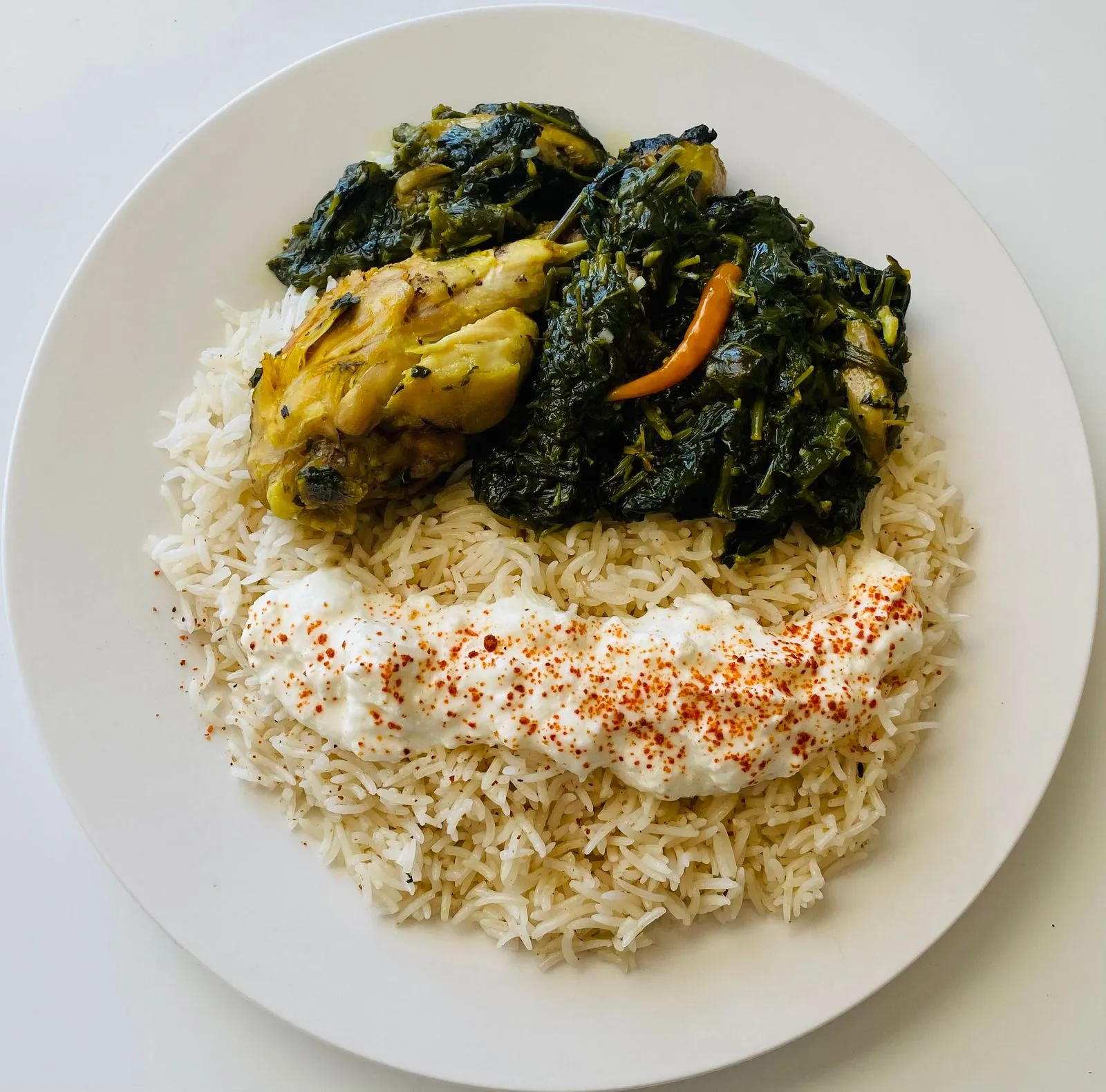Close-up of a savory chicken dish served with rice and vegetables on a plate.